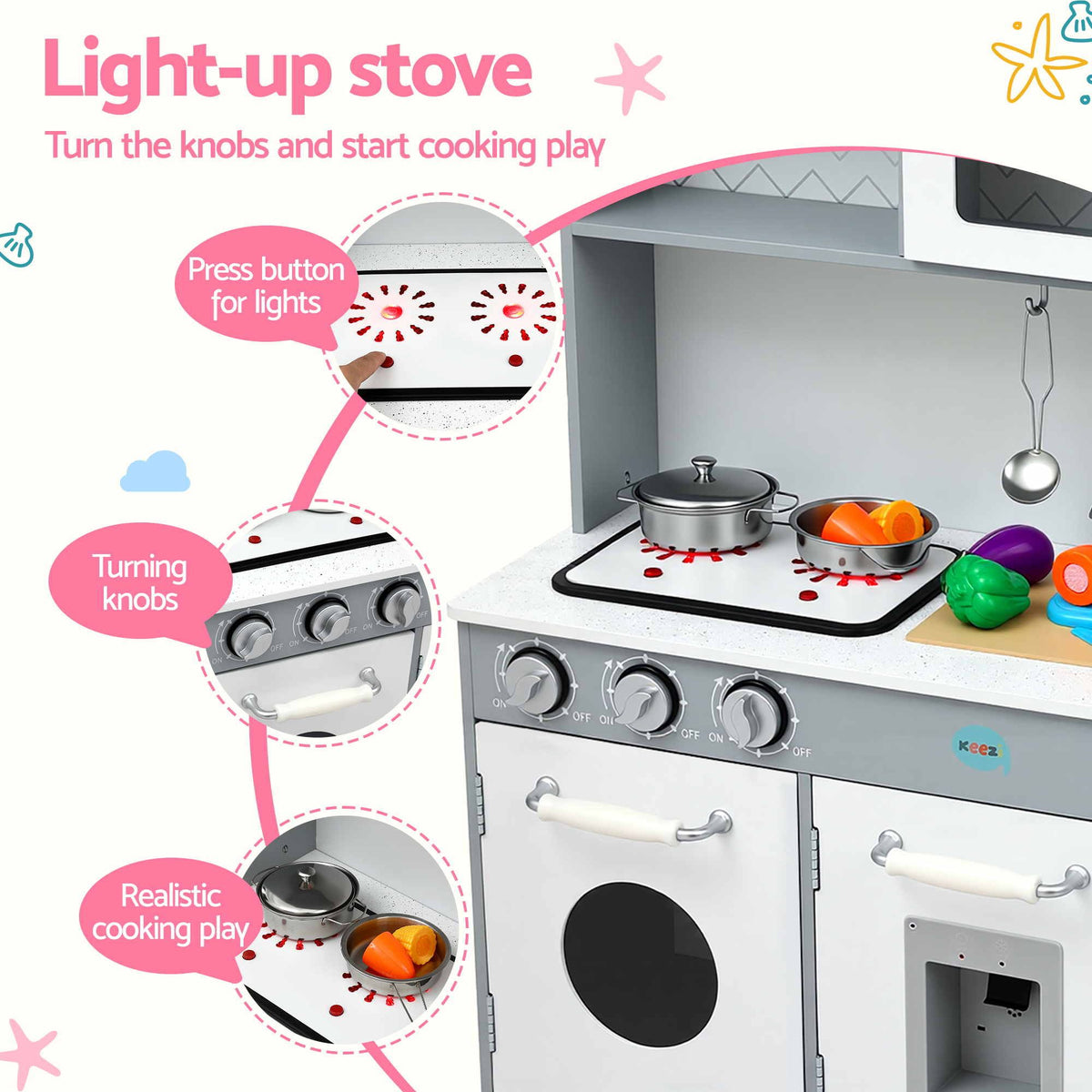 A children's toy play kitchen stove set against a white background with feature callout graphics. The toy stove is white and gray with silver knobs, a black stovetop, and a black cooktop mat with red splatter details.