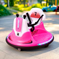 A pink and white electric bumper car ride-on toy with LED lights, shown outdoors on a paved path with a blurred background.