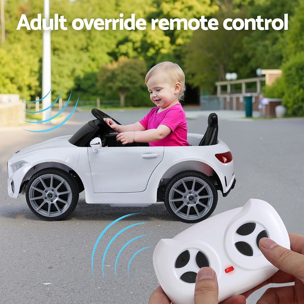 Child playing with a toy car outdoors, holding an adult override remote control.