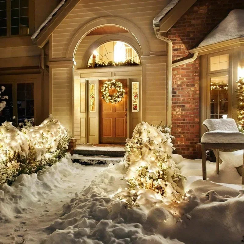 Decorated house entrance with wreath and lights on a snowy day