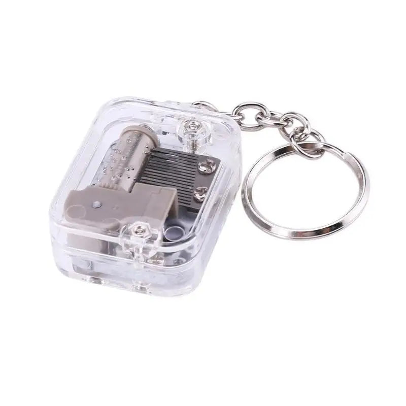 Clear music box keychain with metal components on a white background