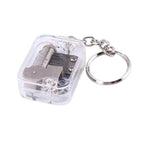 Clear music box keychain with metal components on a white background