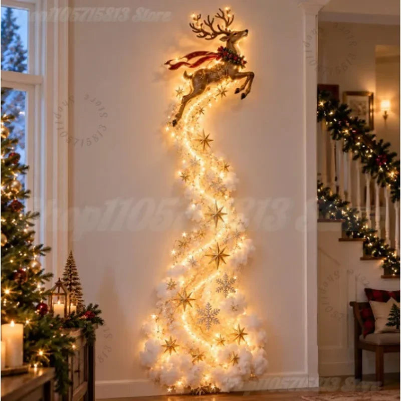 A festive Christmas tree-shaped light and ornament display in a warmly lit indoor hallway. The design features a golden reindeer at the top with a red bow, and a spiral of warm white lights and white fluffy ornaments with gold star and snowflake decorations cascading down the wall.