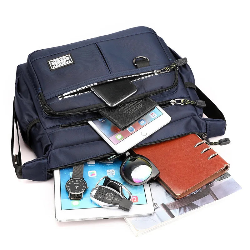 Navy blue backpack with various items including a tablet, phone, and wallet on a white background