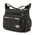 Black shoulder bag with multiple zippers and straps on a white background
