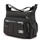 Black shoulder bag with multiple zippers and straps on a white background