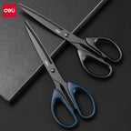 Two pairs of Deli scissors on a dark surface with Deli branding.