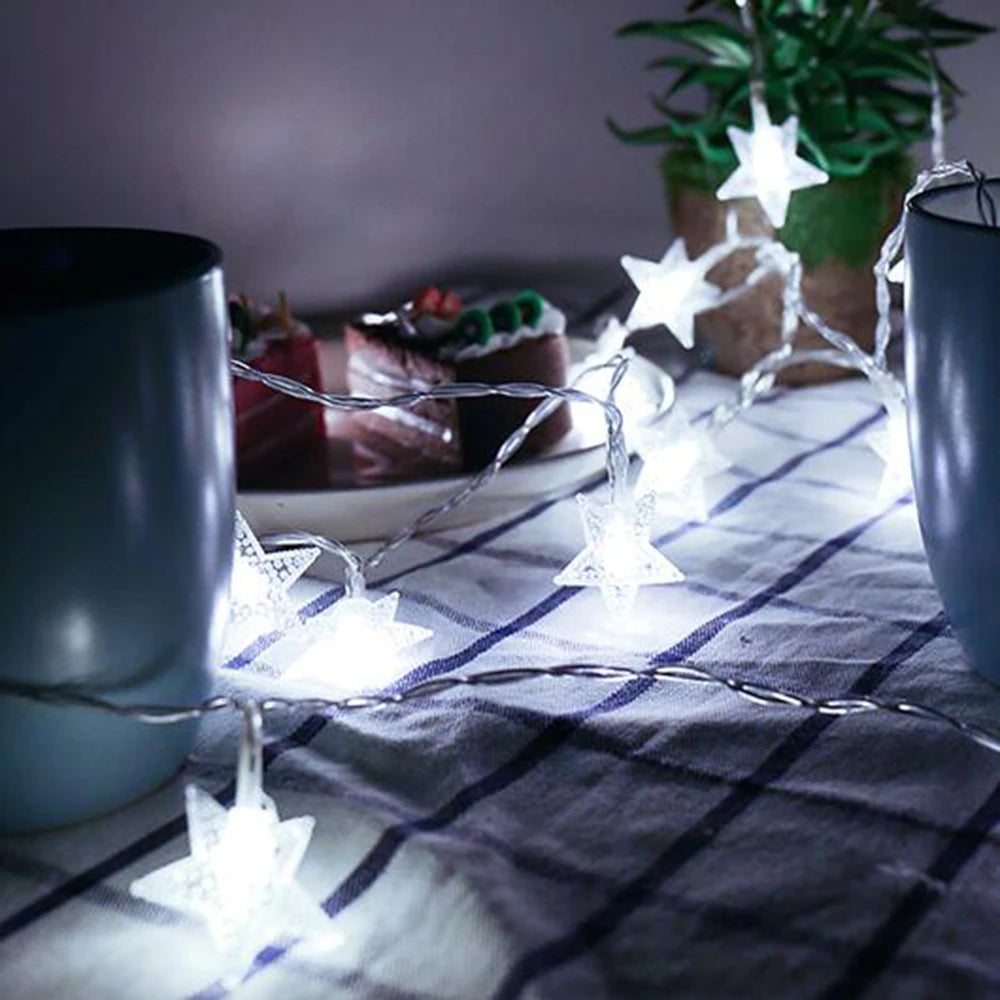 Star-shaped string lights on a table with a cake and cups in the background