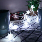 Star-shaped string lights on a table with a cake and cups in the background