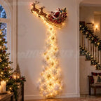 A festive Christmas wall decoration featuring Santa Claus in a sleigh pulled by reindeer, with a long cascading tree of warm white fairy lights and gold and silver star/snowflake ornaments, displayed in a decorated indoor hallway.