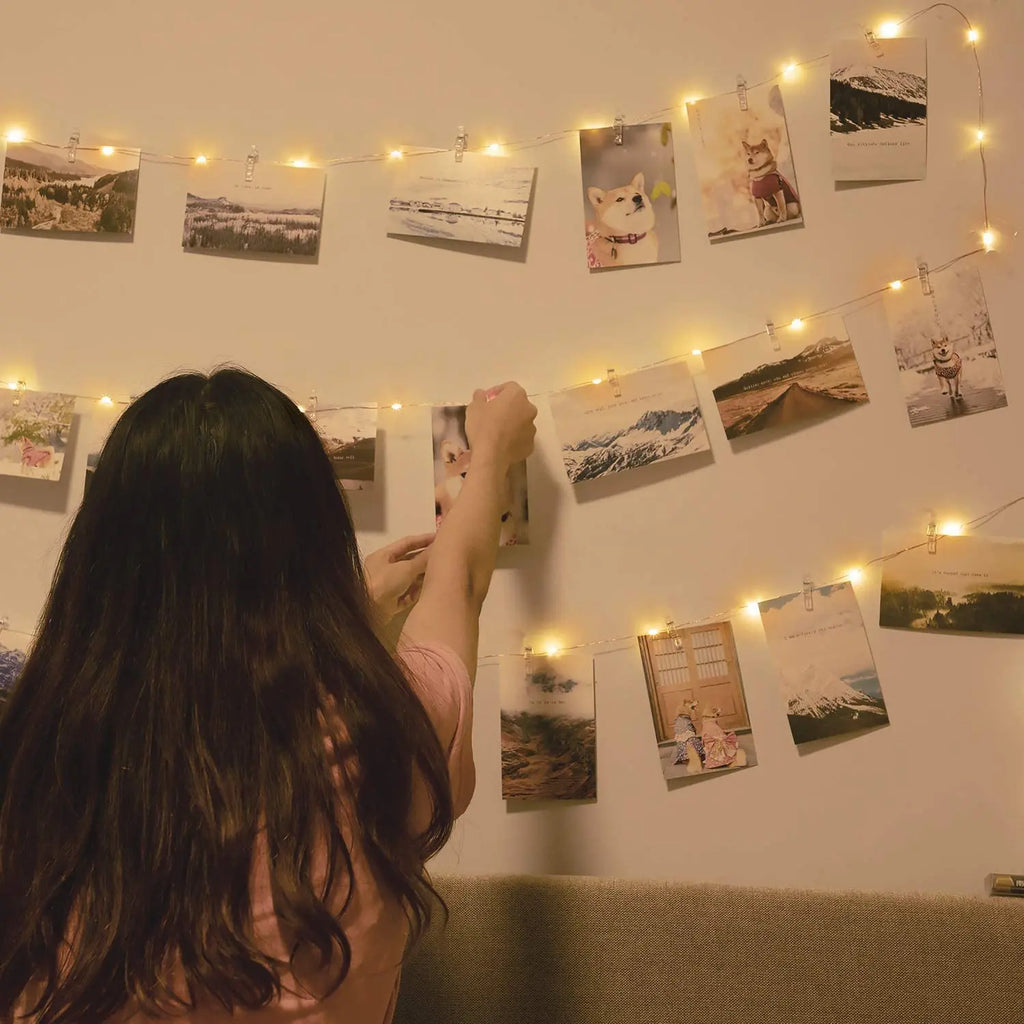 lady hanging photos on light lite wall