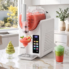 A Devanti slushie maker machine on a marble kitchen counter, shown dispensing a pink slushie into a glass with lime and mint garnish. The machine has a white body, a clear hopper filled with pink slushie, and a digital control screen on the front.