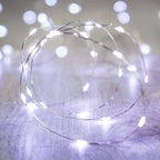 Coiled string of LED lights on a wooden surface with blurred lights in the background