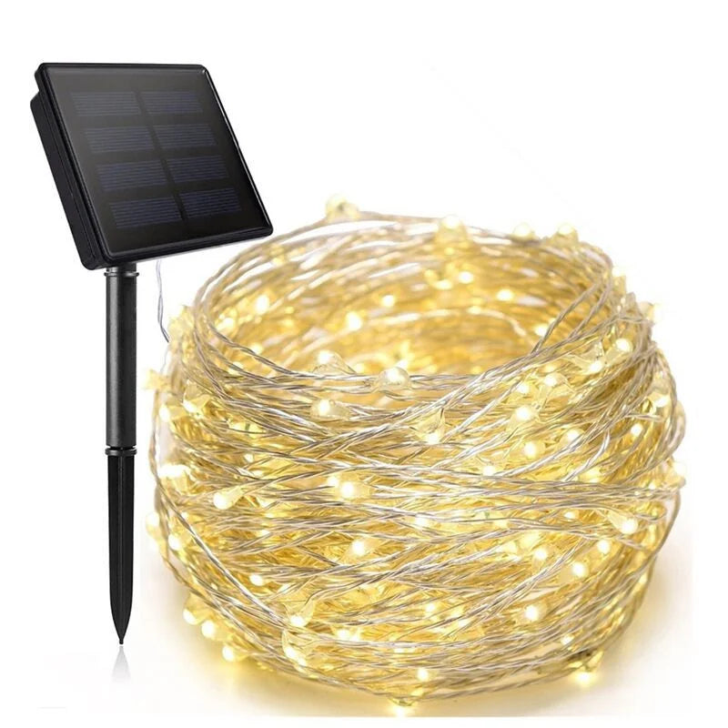 Solar garden string lights with a coiled bundle of warm white LED fairy lights on a wire and a black solar panel stake, shown on a white background.