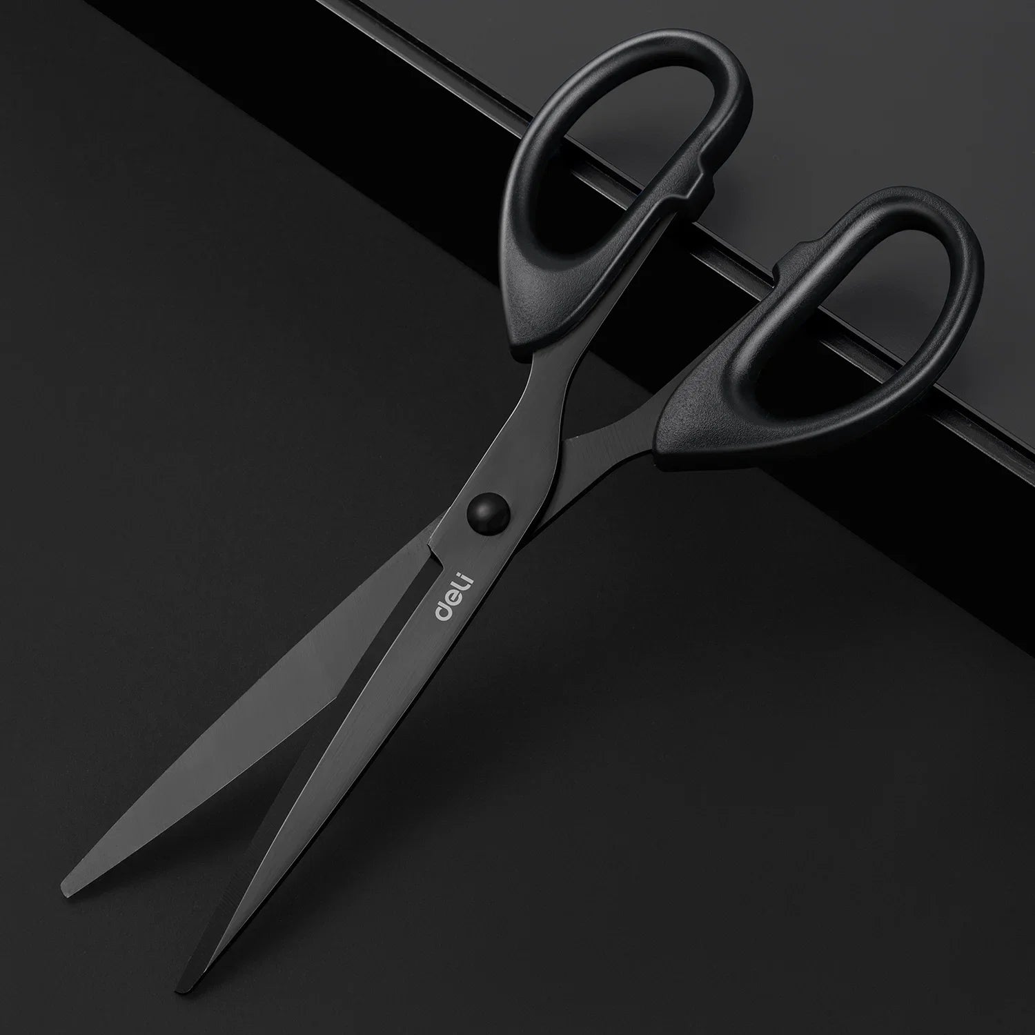 Black scissors with 'deli' branding on a dark background