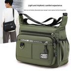 Green shoulder bag with multiple pockets and a person wearing a black bag in the background.