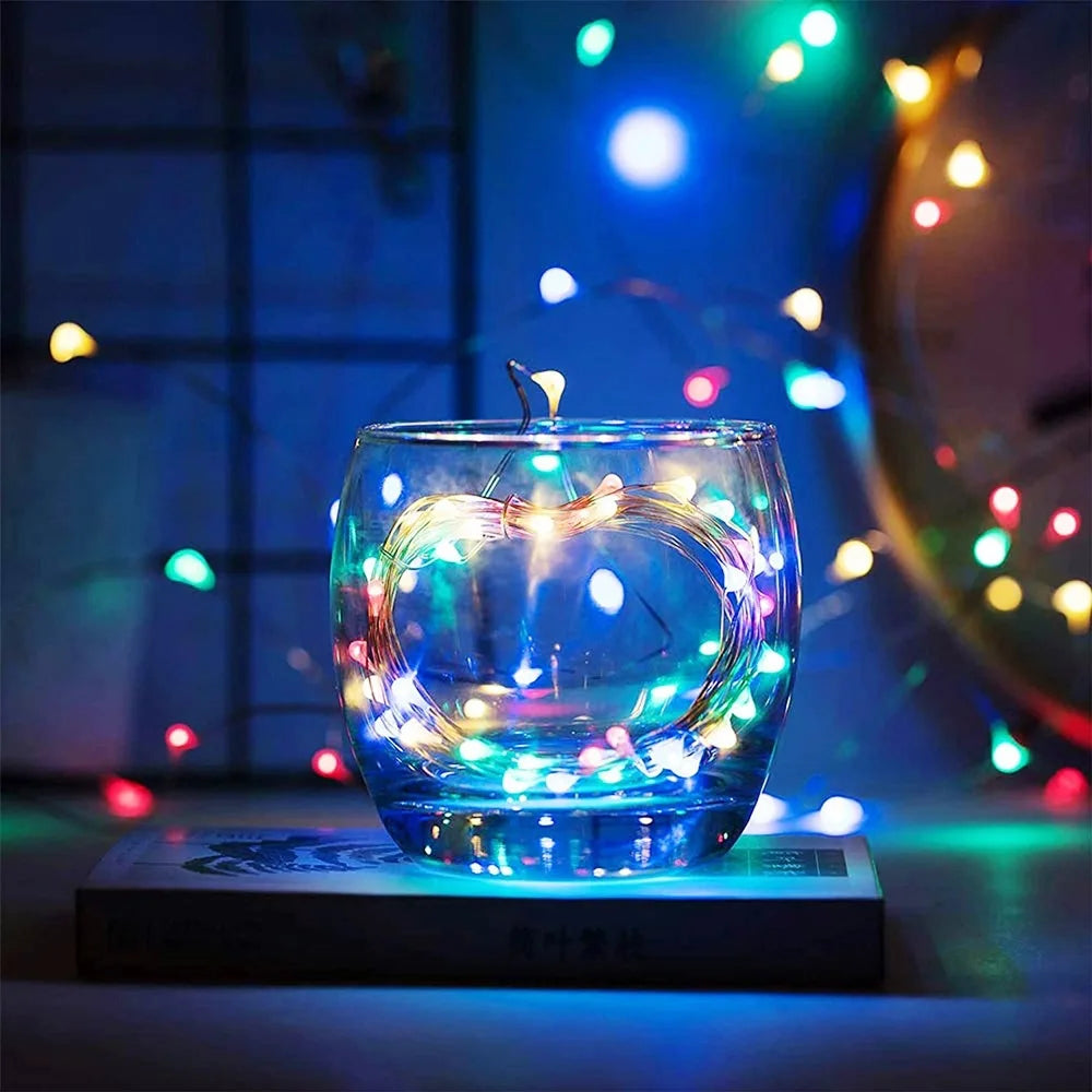 Glass with floating candle and colorful lights on a dark background