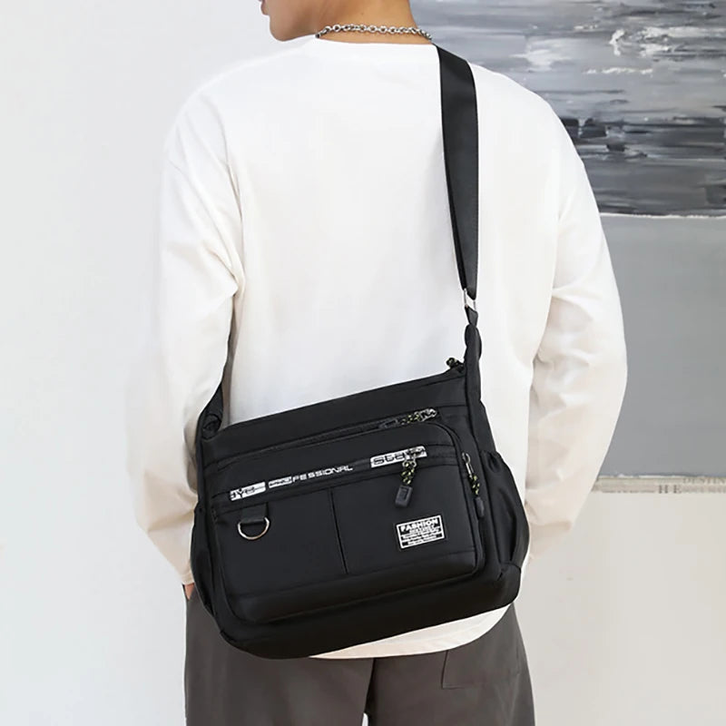 Person wearing a black shoulder bag with visible branding against a neutral background