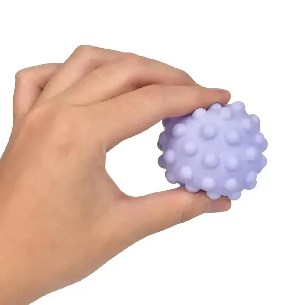 Hand holding a purple textured ball against a white background

