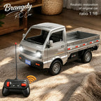 A silver remote-controlled toy pickup truck shown on a beige rug in a home setting, with a black remote control in the foreground and text overlays reading 'Brangdy RC Car' and 'Realistic restoration of original car ratio 1: