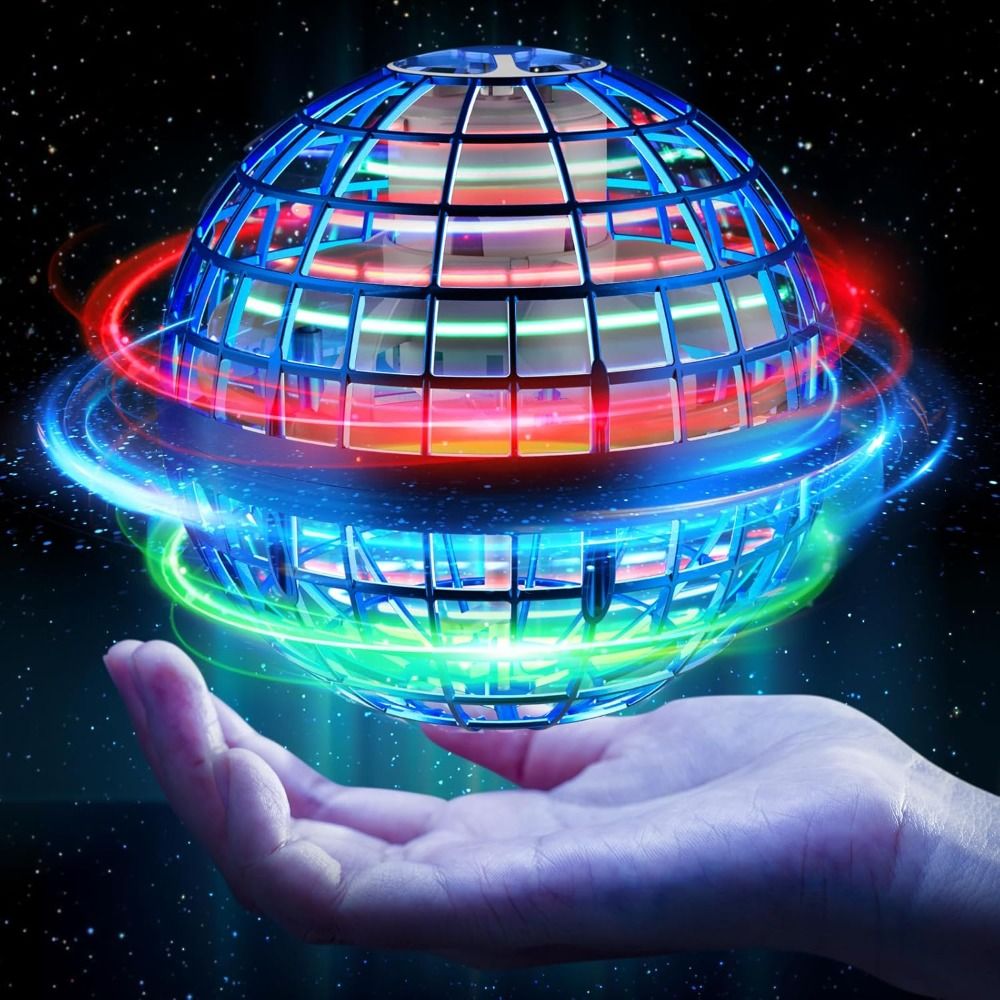 A glowing spherical grid toy floating above an open hand against a starry dark background. The sphere emits bright blue, red, green, and orange light trails, with a small miniature house visible inside the cage-like structure.