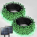 Two coiled bundles of solar string lights with bright green illuminated LEDs and black wiring, shown on a light gray background with two small solar panels pictured in the lower left corn