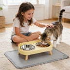 Girl petting a cat eating from a elevated pet feeder in a home setting