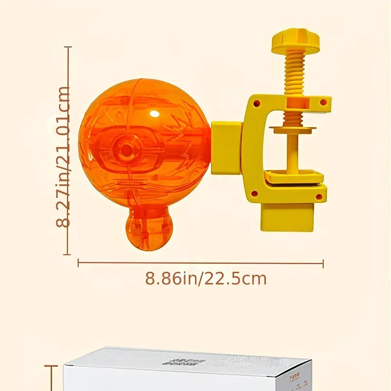An orange translucent spherical toy or ornament with a yellow clamp-like attachment, shown with dimension lines and measurements on a light beige background. A white product box is partially visible at the bottom.
