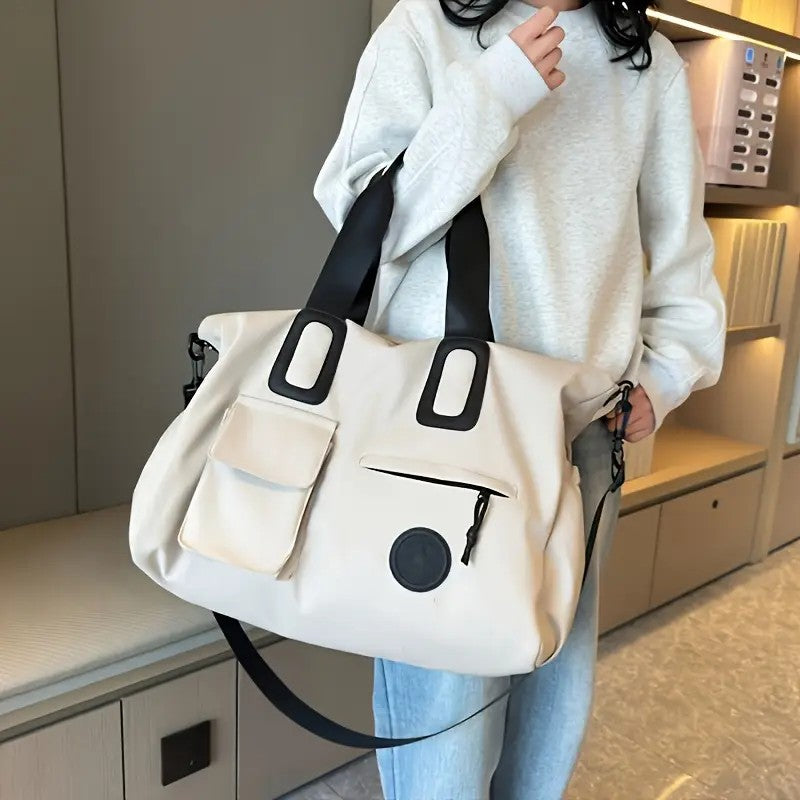 Person holding a white tote bag with black accents in an indoor setting