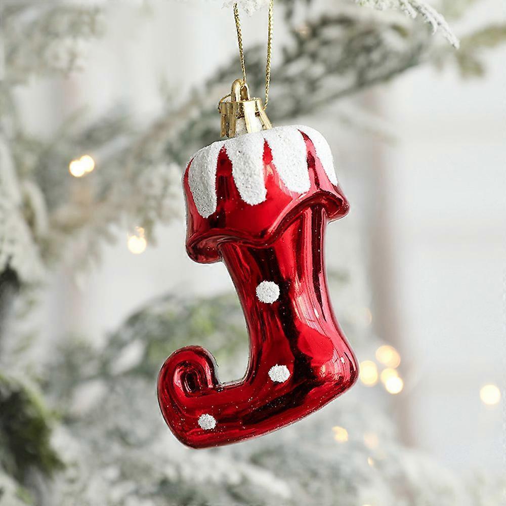 Red glass stocking ornament with white polka dots on a Christmas tree.