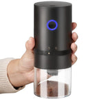 Hand holding a black pepper grinder with a clear body and blue light on a white background