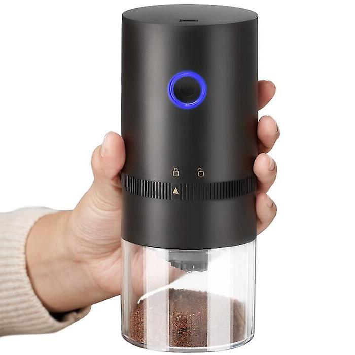 Hand holding a black pepper grinder with a clear body and blue light on a white background