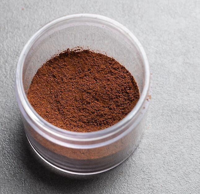 Small container of brown powder on a gray background