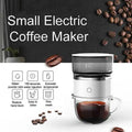 Small electric coffee maker with coffee beans and a cup of coffee on a white background