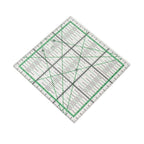 A clear acrylic quilting ruler with green and black measurement markings, shown rotated on a plain white background.