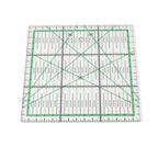 A square clear acrylic quilting ruler with green grid lines, measurement markings, and diagonal guide lines, shown on a plain white background.