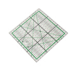 A clear acrylic square quilting ruler with green grid lines and black measurement markings, shown on a plain white background.

