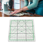 A clear square quilting ruler with green grid lines and black measurement markings, shown below a lifestyle photo of a person sewing fabric at a table.