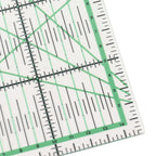 Close-up of a clear acrylic quilting ruler with green and black measurement markings, showing a 14-inch square corner on a white background.