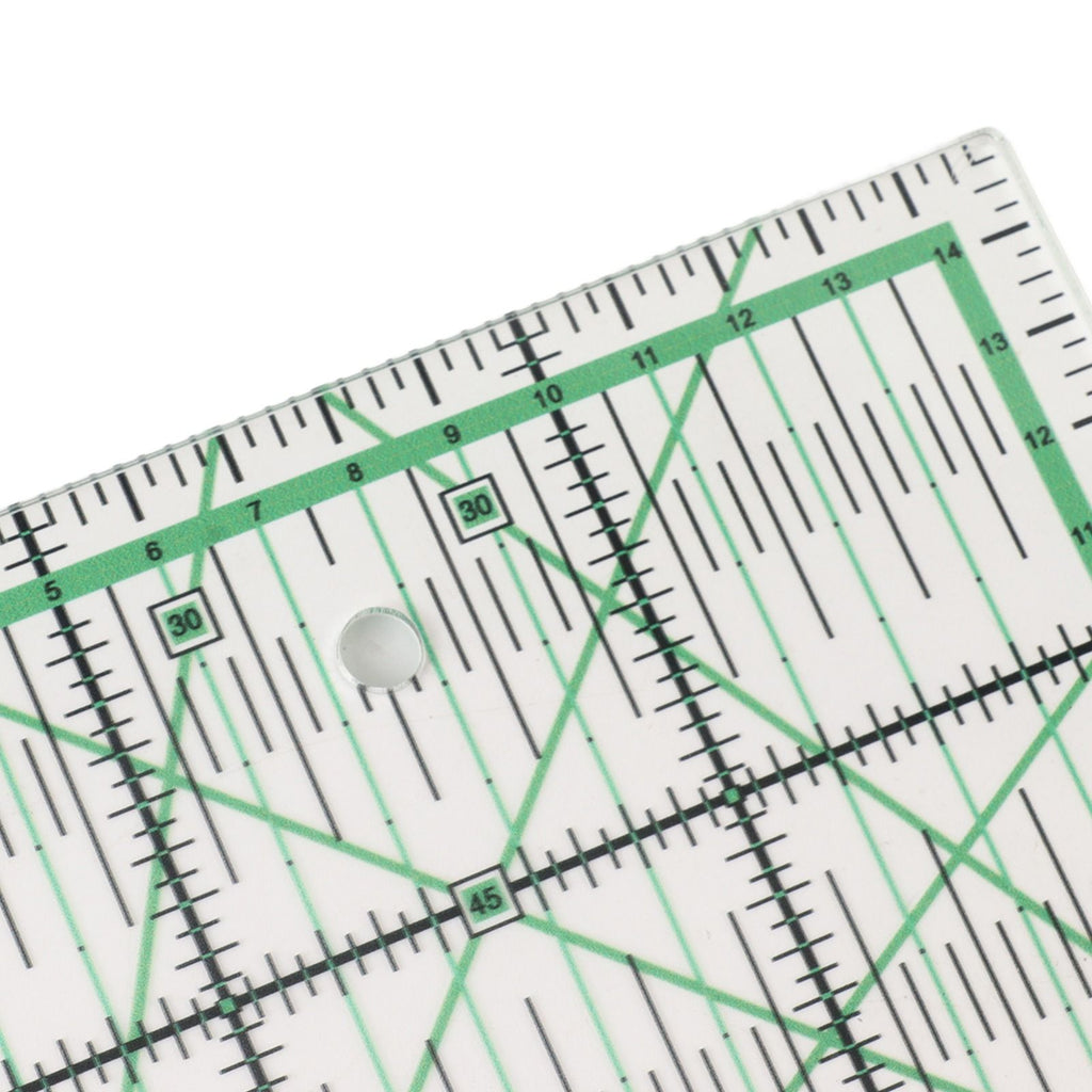 A close-up of a clear acrylic quilting ruler with green and black measurement markings, showing a 90-degree corner and a central hole.