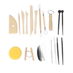 A pottery tool set arranged on a white background, including wooden sculpting knives and spatulas, metal loops and scrapers, pointed sculpting tools, a yellow sponge, and a polished stone or metal slab.