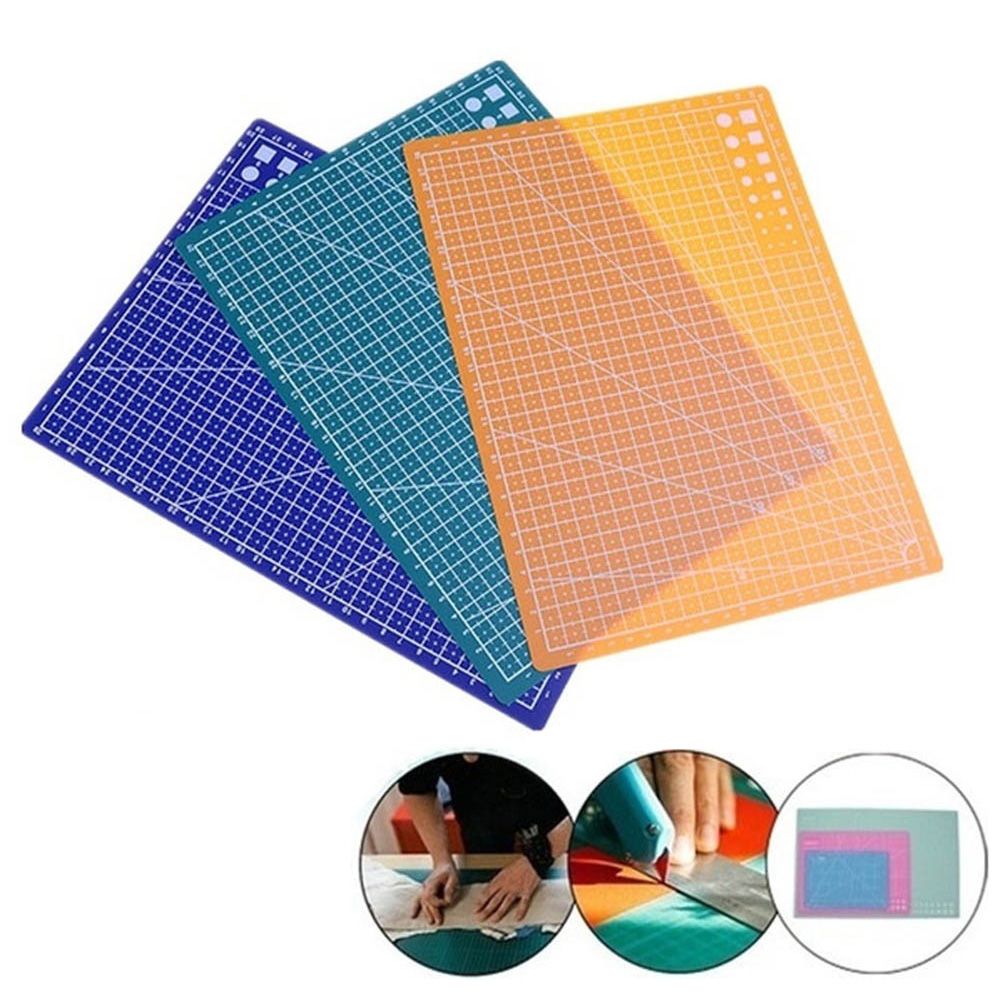 Three translucent cutting mats in blue, teal, and orange-yellow, each printed with a white grid. Two circular inset images at the bottom show the mats in use and a stack of colored mats.