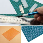 A collage showing a crafting set: a green self-healing cutting mat with grid lines, a blue precision knife with a silver handle being held by a hand, a metal ruler, orange and blue square templates, and small clear plastic containers.
