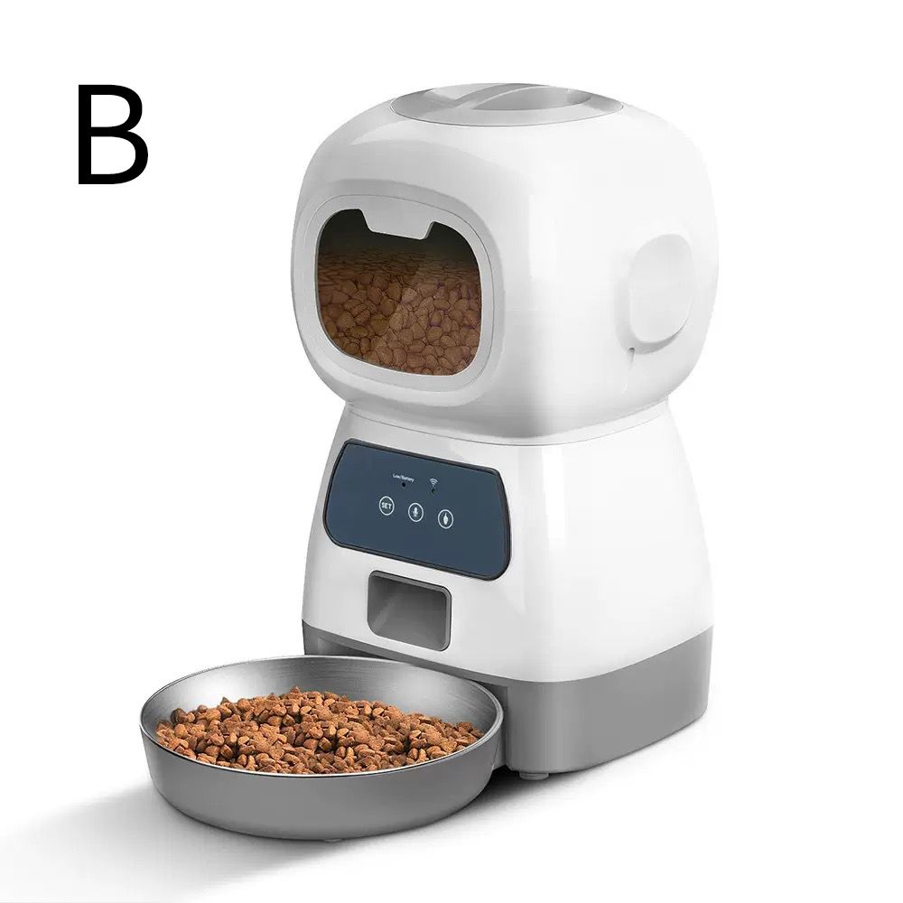 A white and gray automatic pet feeder with a digital control panel, shown with a metal bowl of kibble in front. A black letter 'B' is displayed in the upper left corner.
