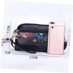 Black pebbled leather crossbody phone bag with a colorful floral patterned front pocket, shown with a smartphone for scale and dimension lines indicating 23cm width, 13cm height, and 3cm depth on a white background.