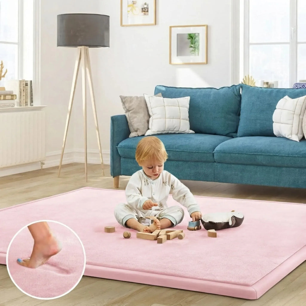 A child sits on a large pink play mat in a bright living room, playing with wooden blocks. A circular inset at the lower left shows a close-up of a foot stepping onto the mat.