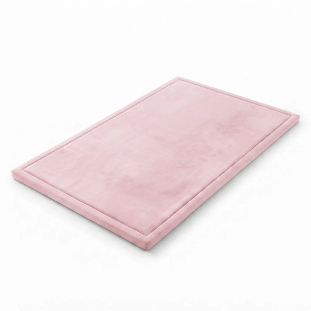 A rectangular pink bath mat with a raised border, shown at an angle on a clean white background.