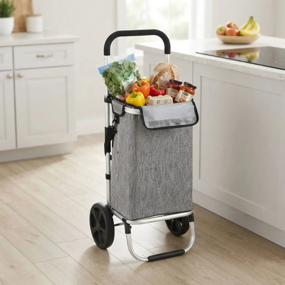 A gray fabric shopping cart with a black handle and wheels, shown in a bright kitchen setting filled with groceries.
