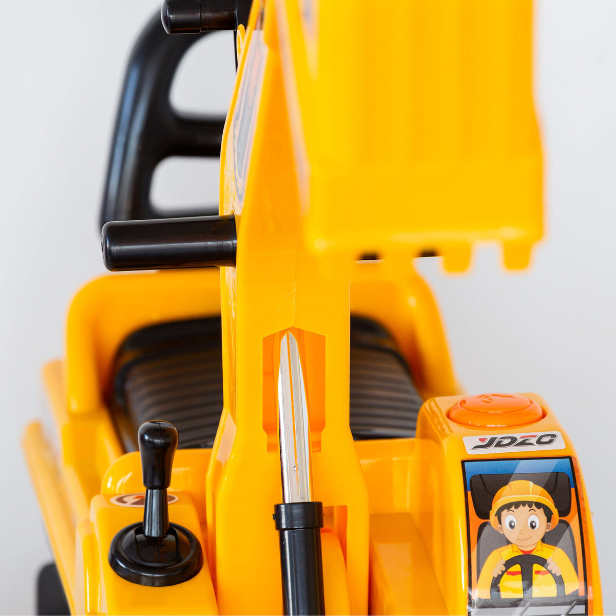 Close-up of a yellow toy excavator with a detailed control panel on a white background