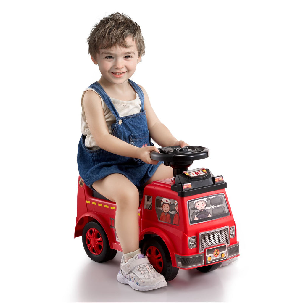Child sitting on a red toy fire truck with a white background